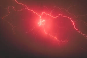 紅色閃電以分支的電能照亮黑暗的暴風雨天空。
