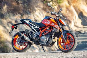 橙色和黑色的KTM Duke電單車停泊在碎石路上，靠近岩石。 — 機車 壁紙