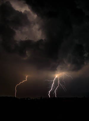 兩道明亮的閃電劃破黑色地平線上的黑暗暴風雲。