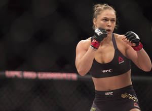 身穿黑色UFC裝備的女性MMA拳手準備在八角籠中戰鬥。