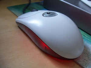 白色Logitech滑鼠，紅色光芒，木桌