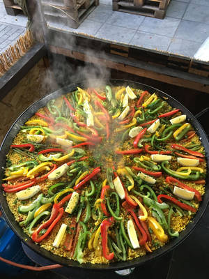 巨大的蒸氣西班牙大鍋飯，搭配色彩繽紛的燈籠椒和檸檬，在露台上 — 3:4 壁紙