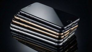一堆黑色、金色和銀色智能手機，在光滑的深色表面上反射