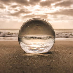 沙灘上的玻璃球反射日落海浪和天空 — 淺綠色美學動態圖 壁紙