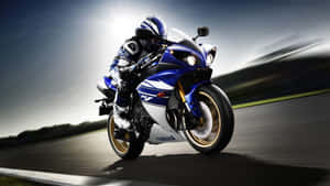 電單車手在日落時分騎著藍色Yamaha R1傾斜入彎。 — 16:9 壁紙