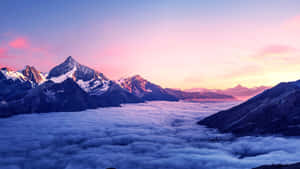 白雪覆蓋的山峰在日出時聳立於雲海之上。