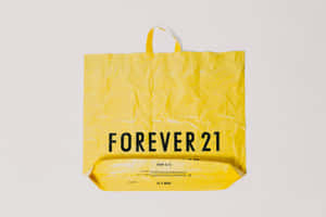 一個黃色Forever 21購物袋，上面有黑色文字，背景為白色。 — 明亮 壁紙