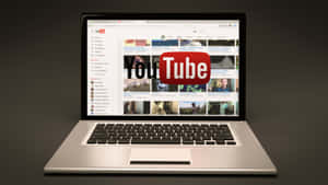 銀色手提電腦顯示YouTube主頁，帶有紅色標誌和影片縮圖。 — YouTube 壁紙