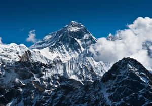 在清澈藍天下，白雪覆蓋的山峰聳立於雲層之上