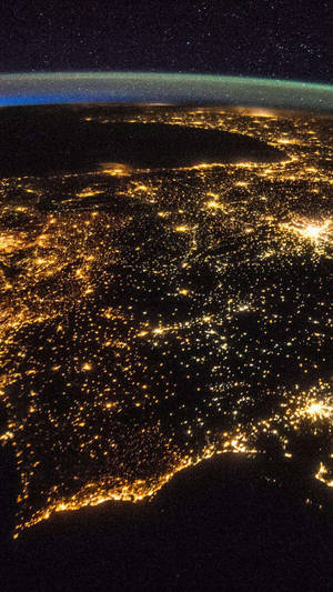 從太空看地球的夜景，顯示閃爍的城市燈光和星空。 — 銀河 壁紙