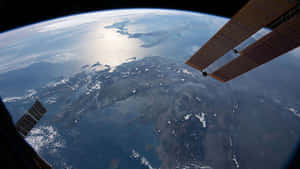 從太空看到的地球，太空船的太陽能板清晰可見 — 太空人 壁紙