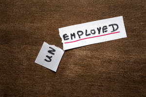 撕破的紙張上 'EMPLOYED' 被劃掉，撕口處露出 'UN'。