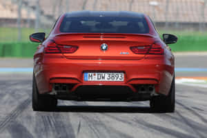紅色BMW M6跑車在賽道上，可見排氣管和車牌。 — Surface Pro 壁紙
