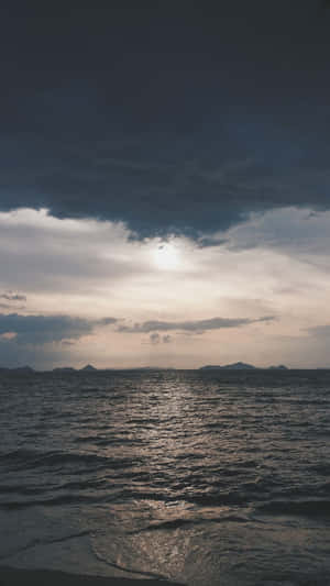 陽光穿透暴風雲，照耀在黑暗的海洋和遠處的島嶼上。