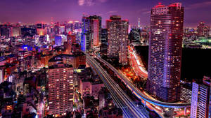 夜晚繁忙的城市，燈火通明的建築物和移動車輛的光軌。