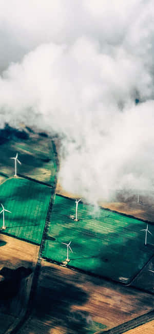 日落時分，飄動的雲朵下農田上的風力發電機。 — Infinix Zero 30 壁紙
