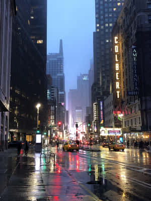 雨夜城市街道，霓虹燈在濕漉漉的人行道和黃色出租車上反射。 — 紐約市 壁紙