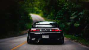 黃昏時分黑色跑車在蜿蜒的森林道路上