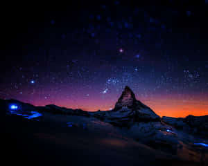 在帶有紫色和橙色色調的星空暮色天空下的積雪山峰。