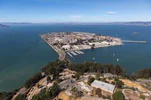 從高空俯瞰海岸島嶼，帆船和建築物被水和綠色山丘環繞。 — 加州 壁紙