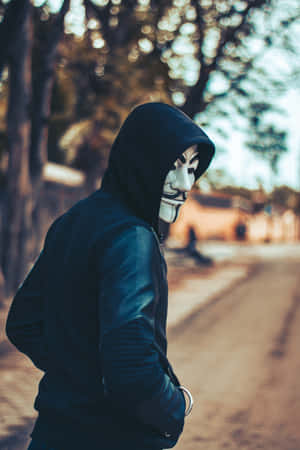 在陽光明媚的街道上，戴著蓋伊·福克斯面具和黑色連帽衫的人。 — 鬼滅之刃面具 壁紙