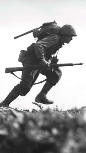 戰時黑白照片中，士兵手持步槍跑上山坡。