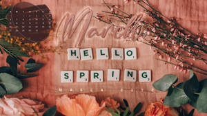 三月日曆，帶有「Hello Spring」拼字遊戲字母牌和粉紅色布料上的鮮花。