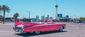 粉紅色復古敞篷車在拉斯維加斯行駛，背景是Stratosphere Tower。