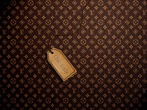 一個棕色皮革標籤，上面有 'Chic Lady' 文字，放在 Louis Vuitton 字母組合圖案上。