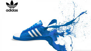 白色背景上帶有顏料飛濺效果的藍色 Adidas 運動鞋。