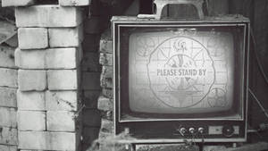 舊電視顯示「Please Stand By」靠在磚牆上