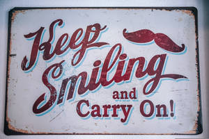 生鏽復古標誌，紅色草書文字和鬍子，寫著 Keep Smiling and Carry On — 鼓舞人心的 壁紙
