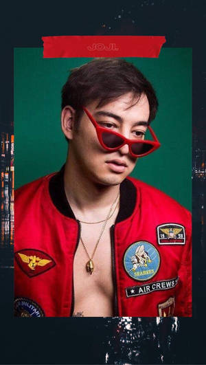 身穿紅色飛行員夾克和太陽眼鏡的男子，在綠色背景前，有城市倒影。