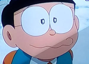 戴著大圓眼鏡、露出微妙笑容的動漫男孩，身穿藍色背心。