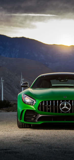 日落時分，綠色Mercedes-AMG GT跑車停泊在風力發電機和山脈附近。