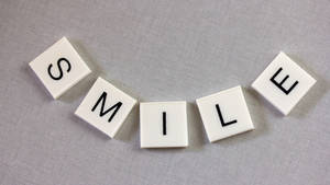 灰色布料上帶有黑色字母拼出 smile 的白色瓷磚。
