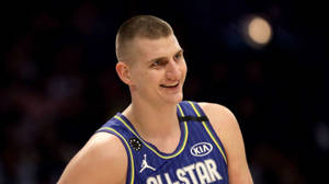 籃球運動員身穿藍色全明星球衣在比賽中微笑。