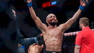 UFC拳手在血腥比賽後於八角籠內高舉雙臂慶祝勝利。