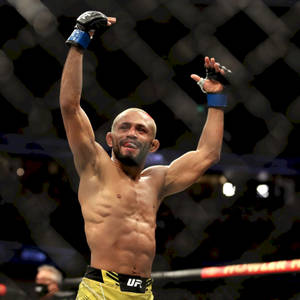 UFC拳手在八角籠內高舉雙臂慶祝勝利。