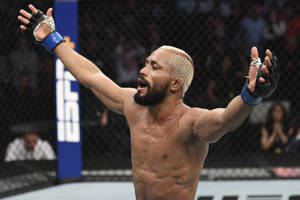 MMA拳手在八角籠內高舉雙臂慶祝勝利。