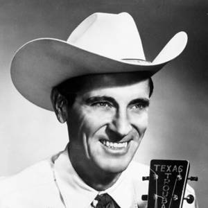 微笑的牛仔音樂家在工作室肖像中拿著Texas Troubadour結他。