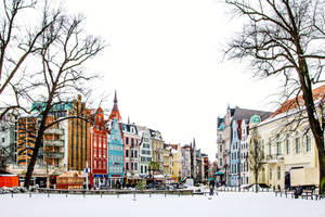 白雪覆蓋的城市廣場，擁有色彩繽紛的歷史建築和光禿禿的樹木。