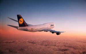 漢莎航空飛機在日落時飛越積雪的山脈。 — 雲朵 壁紙
