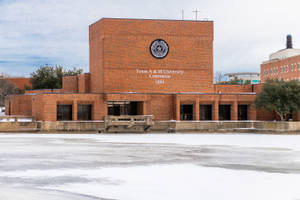 多雲天空下，地面積雪的紅磚大學建築