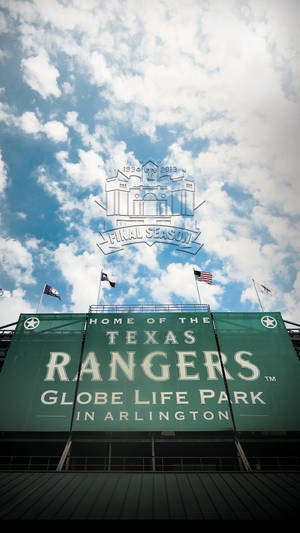 德州遊騎兵隊的Globe Life Park標誌，天空多雲，旗幟飄揚。