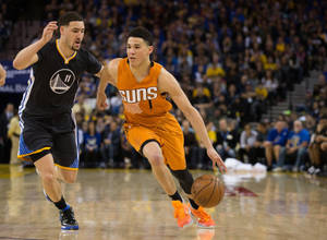 鳳凰城太陽隊球員在NBA比賽中運球越過金州勇士隊防守球員。