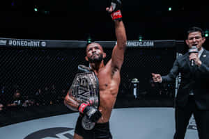 MMA拳手在八角籠中手持冠軍腰帶慶祝勝利。