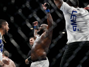 MMA拳手在八角籠內舉起拳頭慶祝勝利。 — 冠軍 壁紙