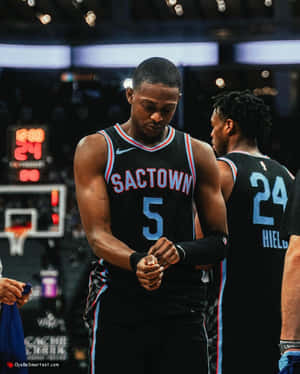 身穿Sactown球衣的籃球運動員在球場上調整護腕。