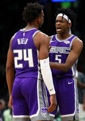 兩名身穿紫色球衣的NBA籃球運動員在球場上激烈交談。